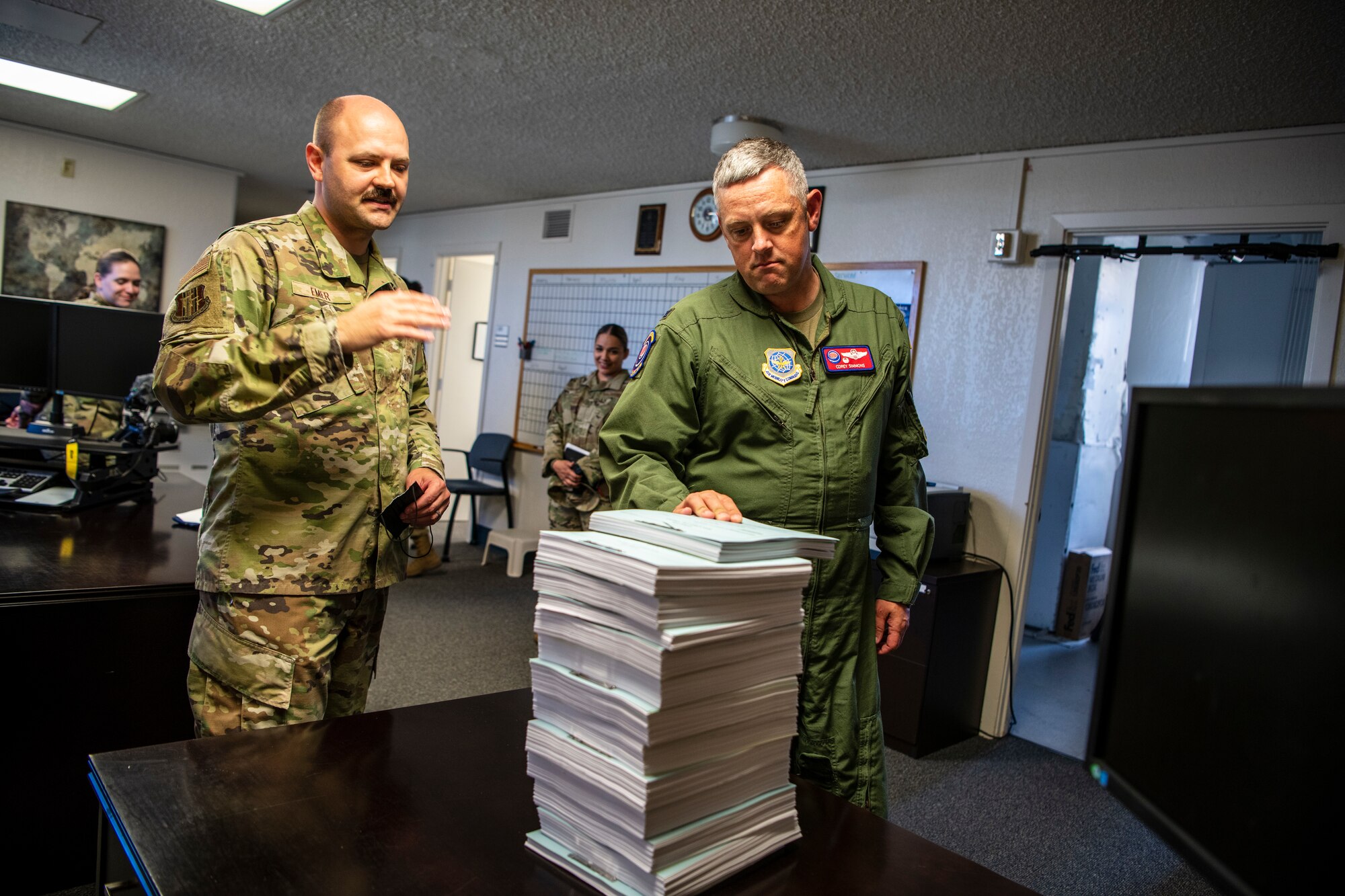 Two Airmen look at a large stack of paperwork from a recent trial.