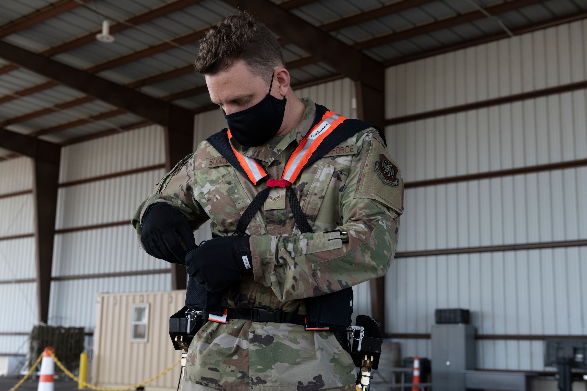 Airman 1st Class Kyle Sunderman, 60th Aerial Port Squadron ramp serviceman, dons Aerial Porter Exoskeleton equipment before demonstrating its capabilities May 14, 2021, at Travis Air Force Base, California. The Aerial Porter Exoskeleton is a piece of equipment designed to reduce strain when lifting various items. (U.S. Air Force photo by Senior Airman Cameron Otte)