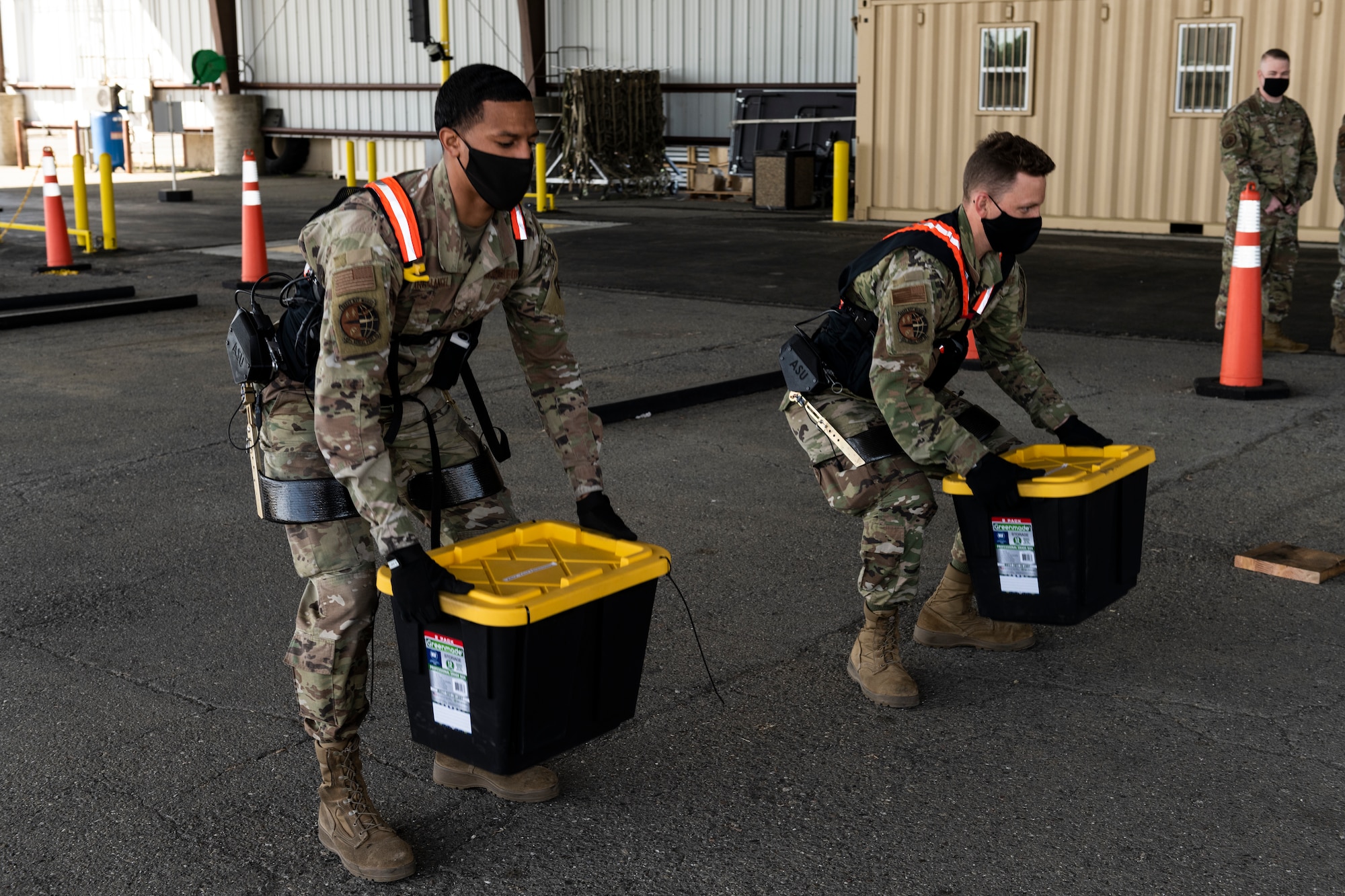 Airman 1st Class Xaviar Archangel, 60th Aerial Port Squadron aerial porter, and Airman 1st Class Kyle Sunderman, 60th APS ramp serviceman, showcase the capabilities of the Aerial Porter Exoskeleton May 14, 2021, at Travis Air Force Base, California. The Aerial Porter Exoskeleton is a piece of equipment designed to reduce strain when lifting various items. (U.S. Air Force photo by Senior Airman Cameron Otte)