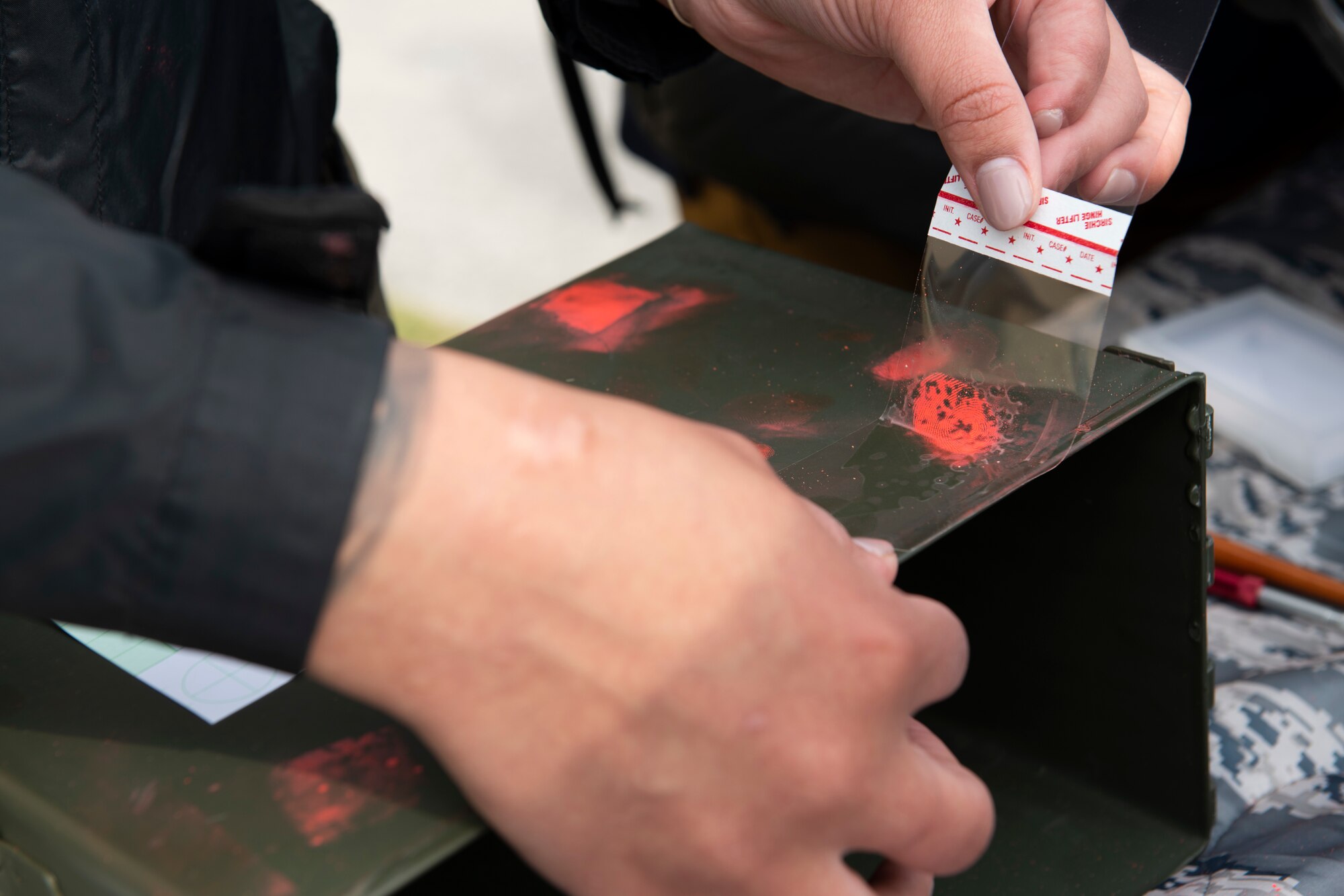 Investigator Kirsten Lopez, 374th Security Forces Squadron, demonstrates how to lift a fingerprint at the “Day in the Life” event during National Police Week at Yokota Air Base, Japan, May 11, 2021. This event allowed the 374th SFS to showcase the different aspects that go into protecting the base as a defender. (U.S. Air Force photo by Staff Sgt. Joshua Edwards)