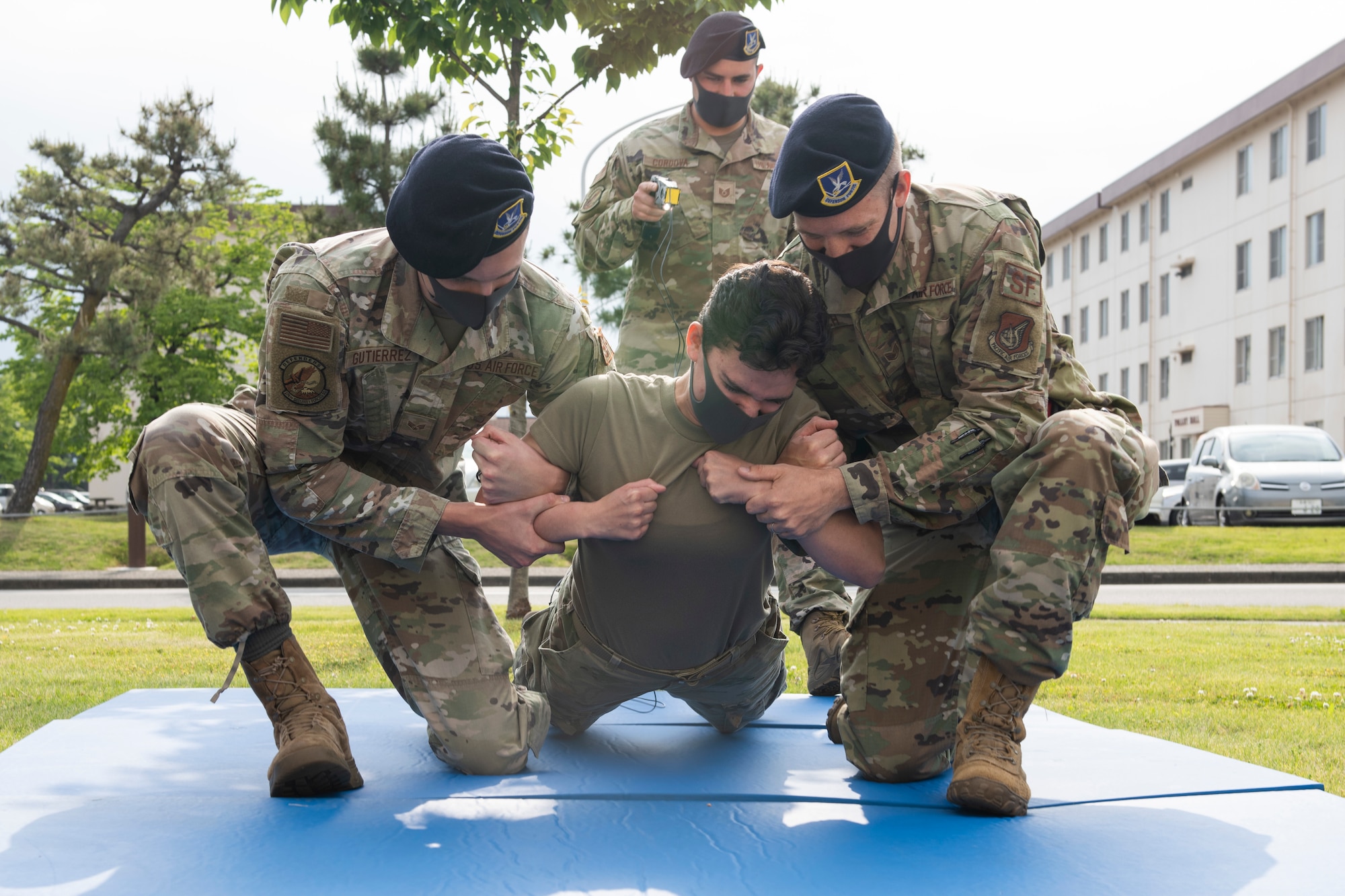 Airman 1st Class Savannah Trevino, 374th Security Forces Squadron Security Response Team member, middle, gets tased at the “Day in the Life” event during National Police Week at Yokota Air Base, Japan, May 11, 2021.  The SFS allowed volunteers to get tased as an educational tool of the effects it has to the body. (U.S. Air Force photo by Staff Sgt. Joshua Edwards)