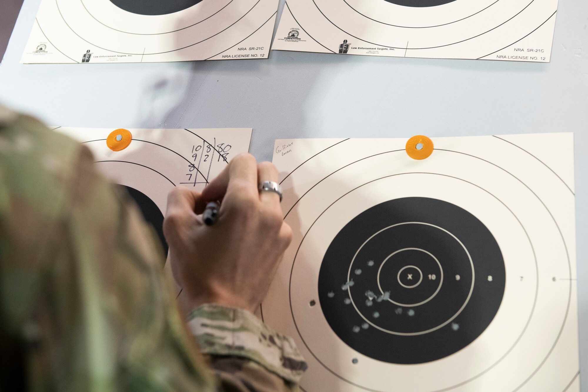 Staff Sgt. Boaz Rogel, 374th Security Forces Squadron Combat Arms instructor, calculates points on a target sheet during National Police Week shooting competition at Yokota Air Base, Japan, May 12, 2021. Competitors received points for hitting the center black area and the top 10 percent received an award. (U.S. Air Force photo by Staff Sgt. Joshua Edwards)