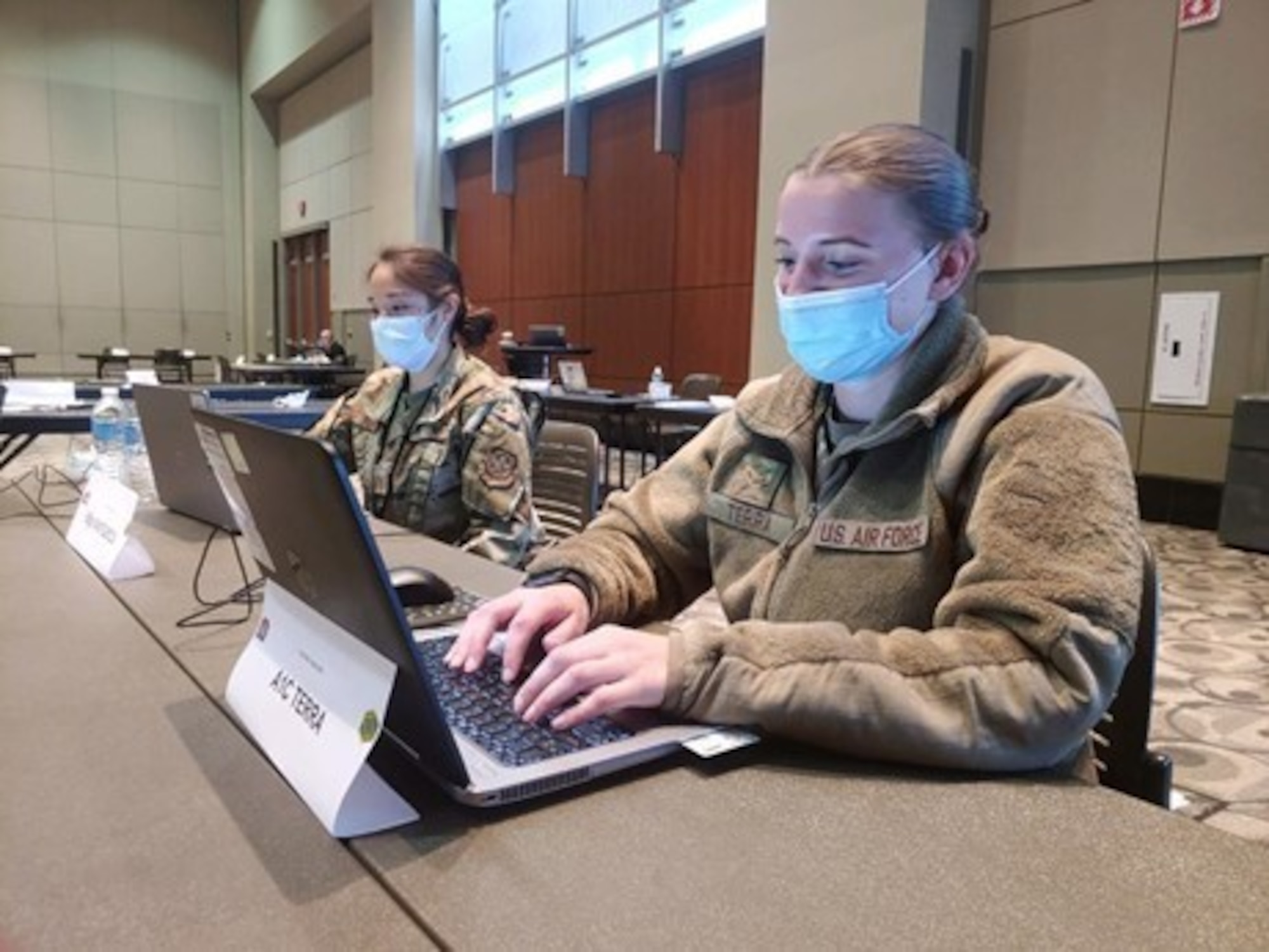 U.S. Air Force Airman First Class Katie Terra, right, a Santa Rosa, California native and admin personnel with the 325th Force Support Squadron, stationed at Tyndall Air Force Base, Florida, assigned to the 4th Detachment, 64th Air Expeditionary Group, provides updated daily accountability reports to the command staff at the federally supported Community Vaccination Site at DeVos Place in Grand Rapids, Michigan, 4 May 2021. Terra is responsible for the sites Personnel Support for Contingency Operations (PERSCO), recently in-processing 117 deployed Air Force members as they began their mission to vaccinate the local population. “I am grateful for this opportunity of meeting new Airmen and learning new tasks that I will use in my Air Force career once our mission is complete. I am excited to see Airmen come together from all over the country and to work together to assist in putting a stop to COVID-19.” U.S. Northern Command, through U.S. Army North, remains committed to providing continued, flexible Department of Defense support to the Federal Emergency Management Agency as part of the whole-of-government response to COVID-19. (U.S. Air Force photo by Senior Master Sgt. Charles Murphy, 64th Air Expeditionary Group, 4th Detachment.)