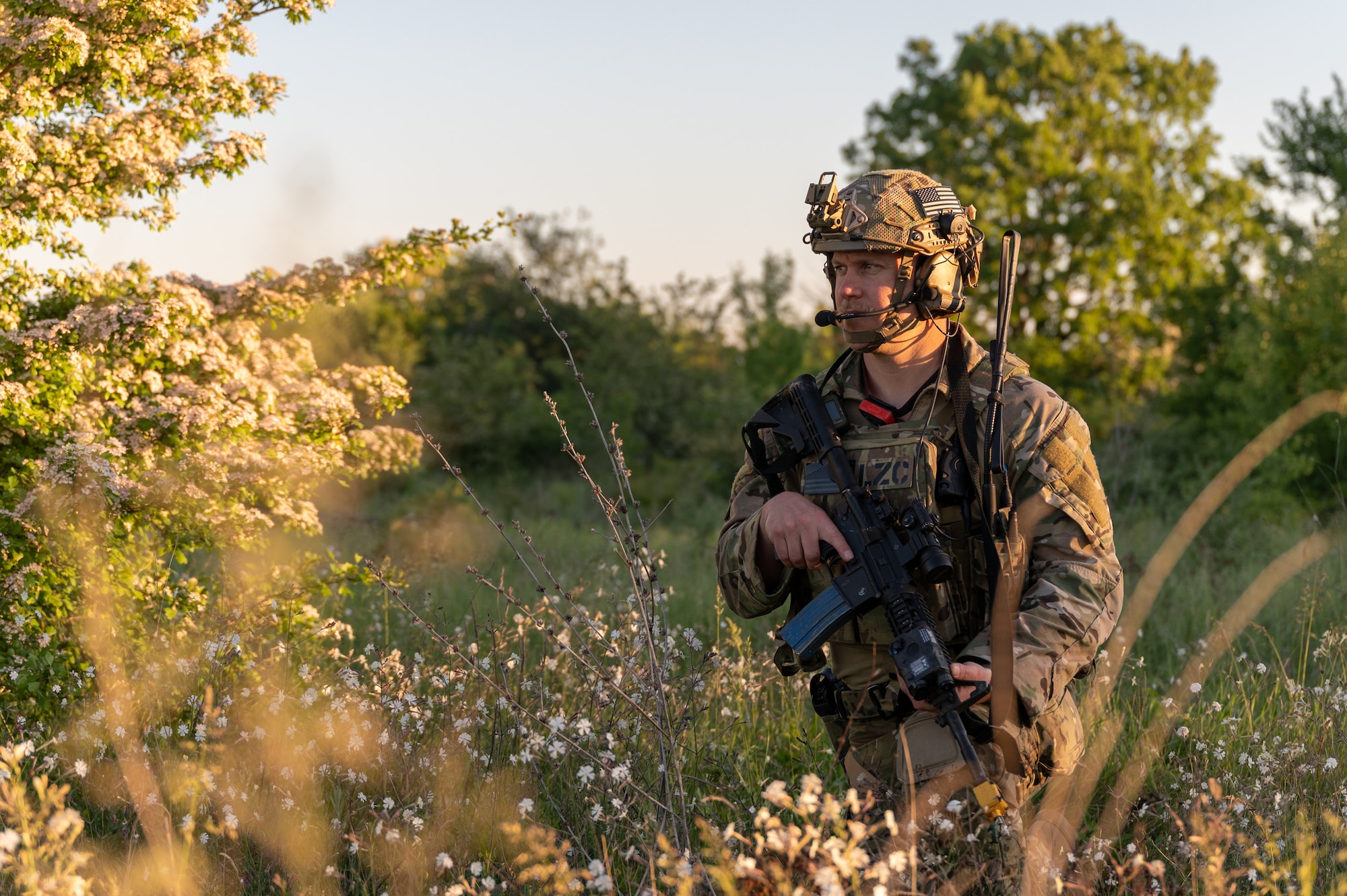 An Airman standing in a field, holding a weapon.