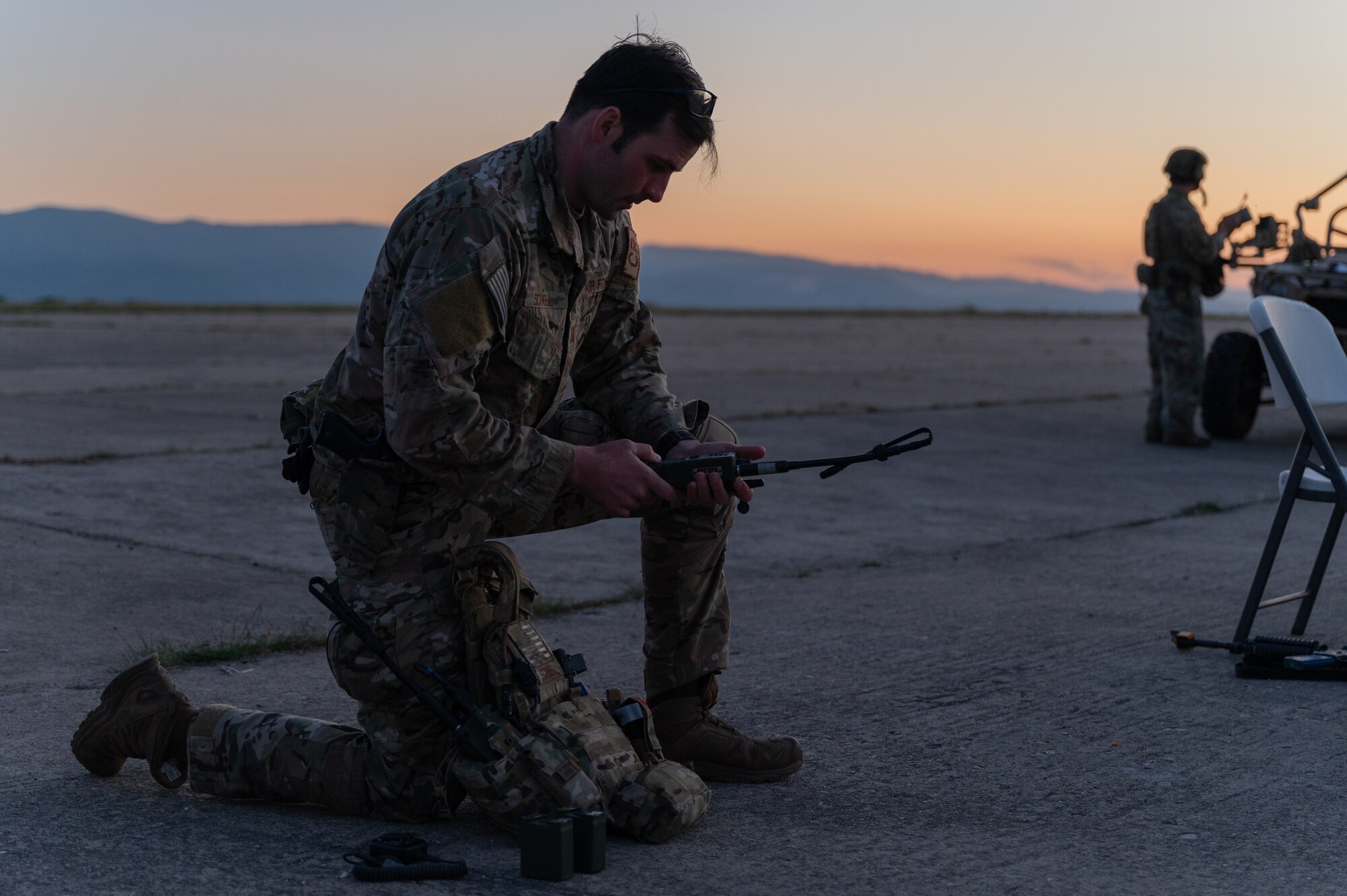 An Airman kneeling on an airfield.