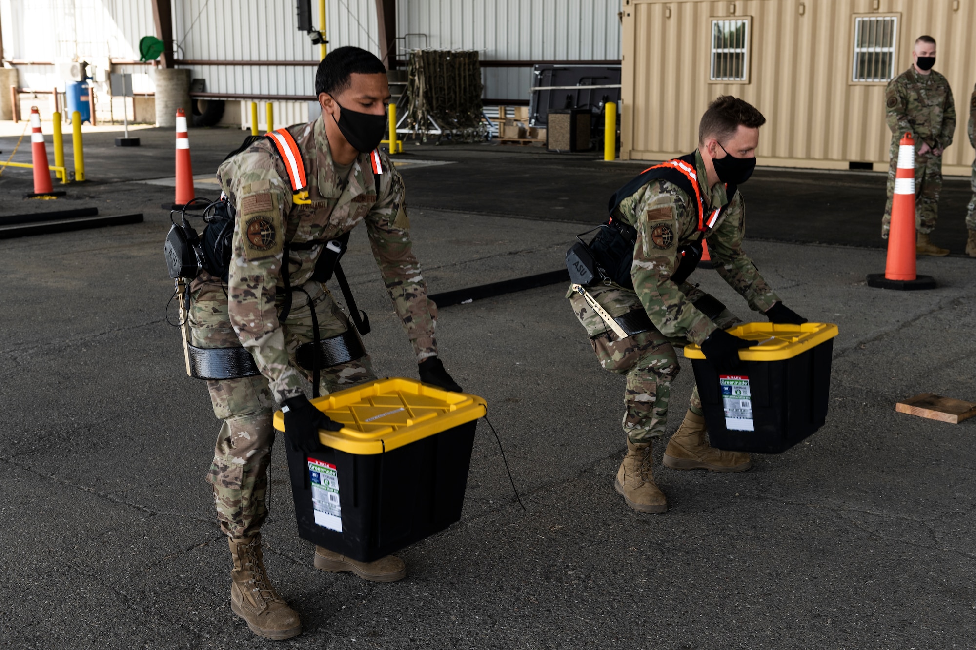 Airman 1st Class Xaviar Archangel, 60th Aerial Port Squadron aerial porter, and Airman 1st Class Kyle Sunderman, 60th APS ramp serviceman, showcase the capabilities of the Aerial Porter Exoskeleton May 14, 2021, at Travis Air Force Base, Calif. The exoskeleton is a piece of equipment designed to reduce strain when lifting various items.