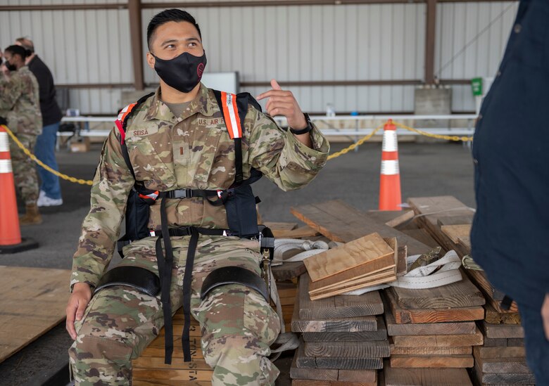 Second Lt. Germaine Seisa, 60th Logistic Readiness Squadron officer in charge of vehicle management, tries on the Aerial Porter Exoskeleton May 14, 2021, at Travis Air Force Base, Calif.. The exoskeleton is a piece of equipment designed to reduce strain when lifting various items.