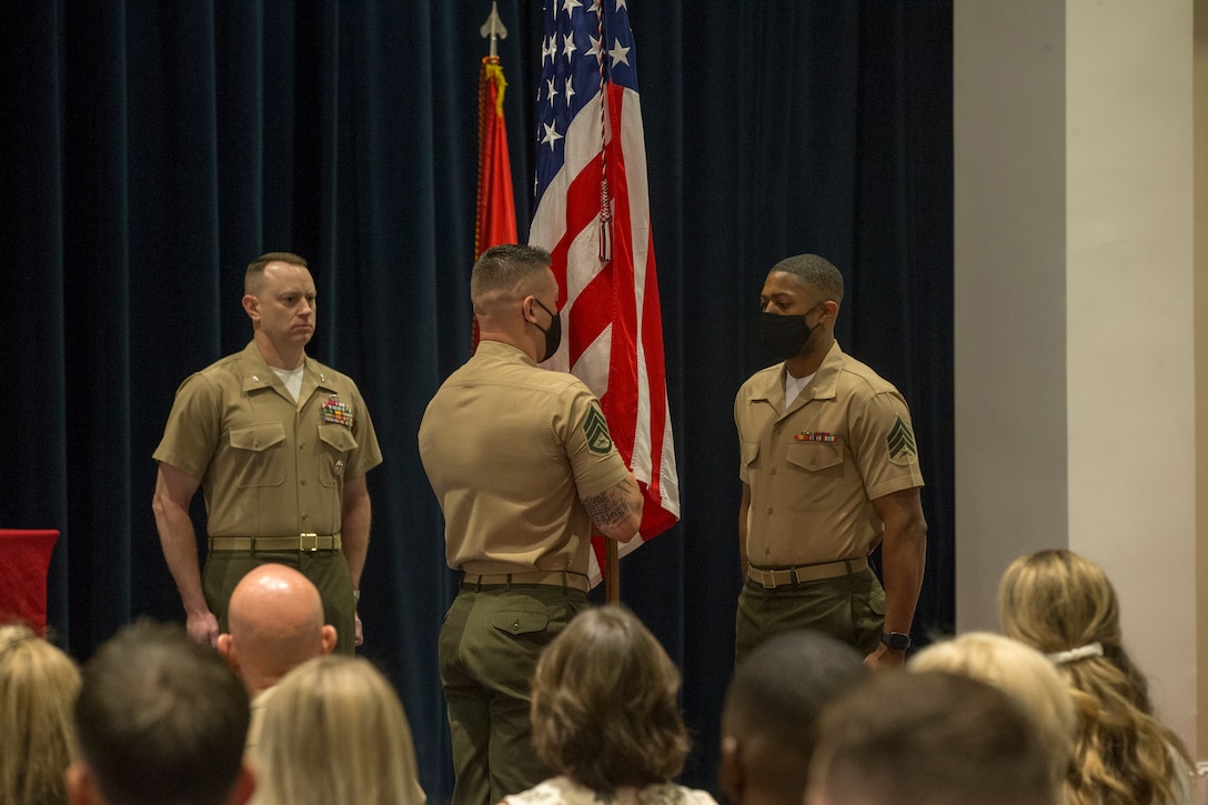 Colonel Teague A. Pastel, commanding officer, Marine Barracks Washington, stands at the position of attention while Staff Sgt. Franklin D. Taft, 39th Color Sergeant of the Marine Corps, passes the National Ensign to Sgt. Cameron Williams, 40th Color Sergeant of the Marine Corps, during the Color Sergeant of the Marine Corps relief and appointment ceremony at Marine Barracks Washington, D.C., May 17, 2021. The Color Sergeant of the Marine Corps serves as the senior sergeant of the Corps, entrusted with carrying the National Ensign in ceremonies throughout the National Capital Region and across the nation. The Color Sergeant leads the official Color Guard Platoon at MBW at is responsible for training and preparing the Marines for future service in the operating forces. (U.S. Marine Corps photo by Lance Cpl. Mark Morales)