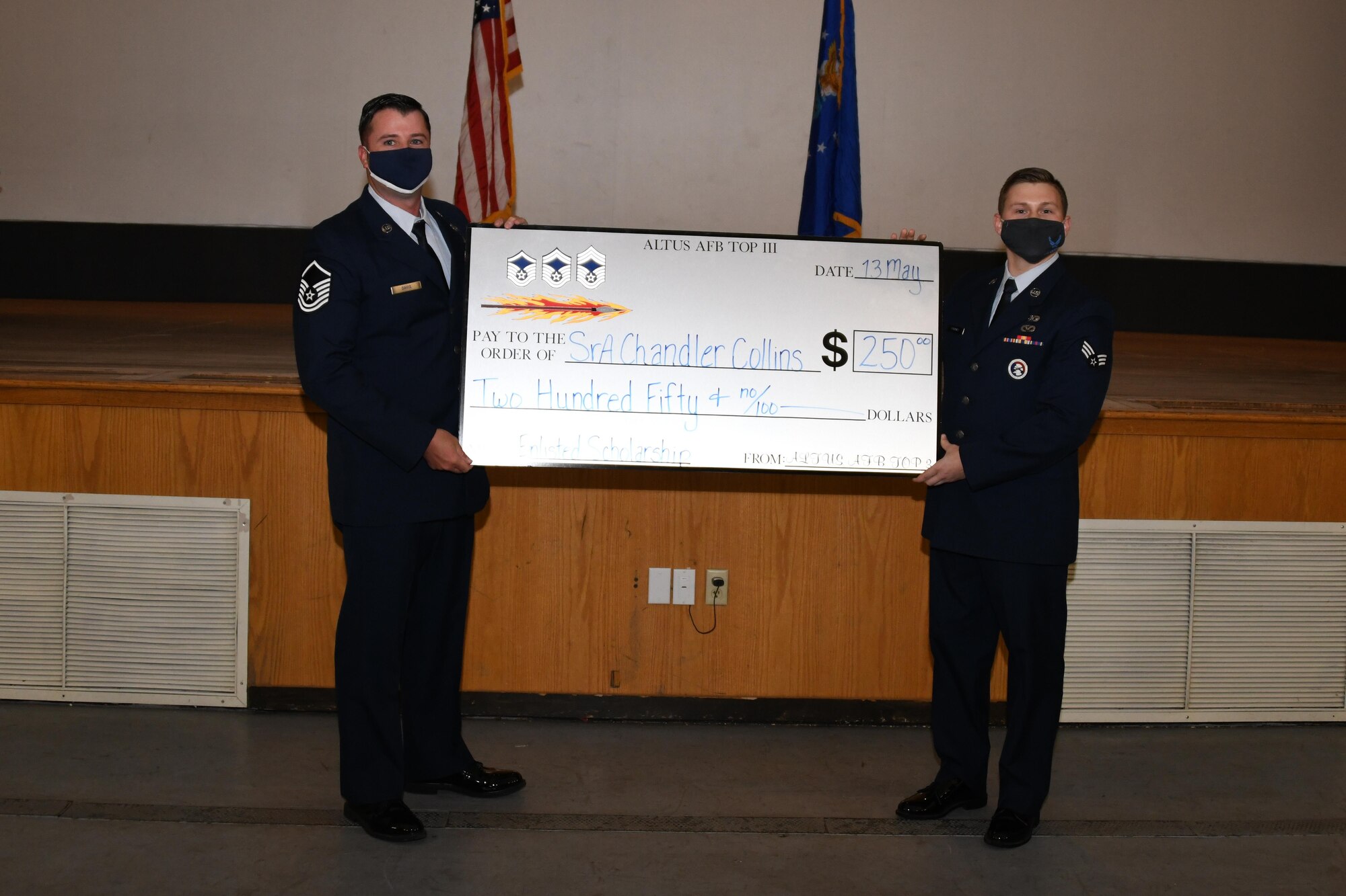 Two men hold large check.
