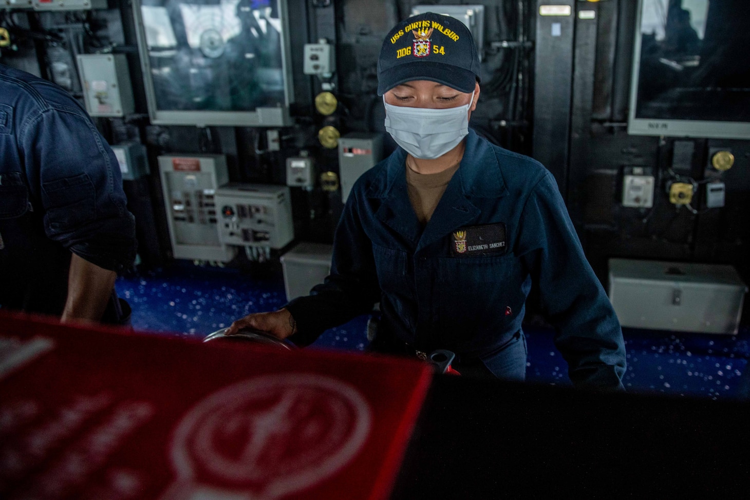 TAIWAN STRAIT (May 18, 2021) – Boatswain’s Mate Seaman Elizabeth Sanchez, from Houston, mans the helm on the bridge of the Arleigh Burke-class guided-missile destroyer USS Curtis Wilbur (DDG 54) as the ship conducts routine operations. Curtis Wilbur is assigned to Commander, Task Force 71/Destroyer Squadron (DESRON) 15, the Navy’s largest forward DESRON and the U.S. 7th Fleet’s principal surface force. (U.S. Navy photo by Mass Communication Specialist 3rd Class Zenaida Roth)