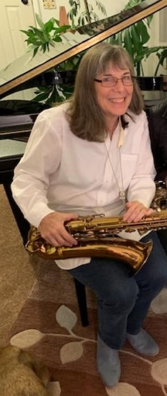 A woman holding an instrument poses for a photo.