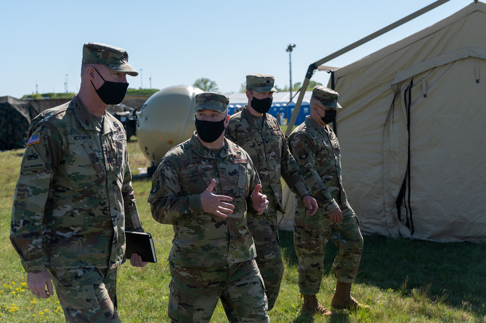 Four men walking side-by-side outside a tent.