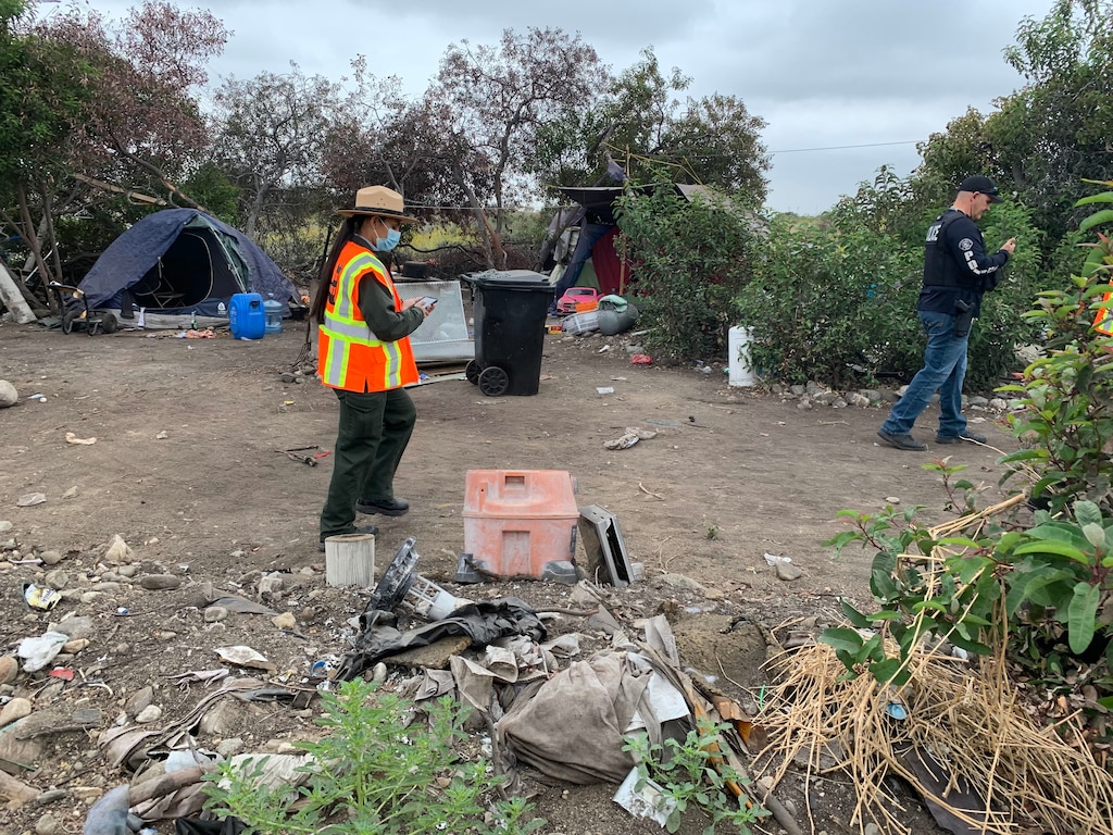 Park Ranger Annel Monsalvo, U.S. Army Corps of Engineers Los Angeles District, investigates one of dozens of abandoned campsites below the Santa Fe Dam, May 10, before crews arrive to clear out the debris.