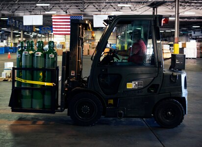 60th Aerial Port Squadron heavy equipment operator moves oxygen tanks