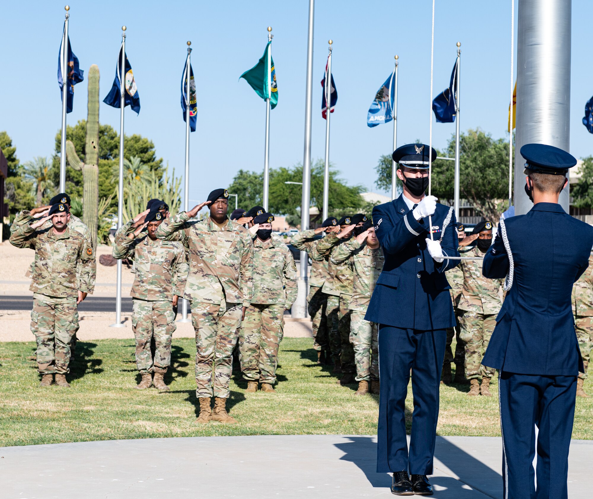 Airmen from the 56th Security Forces Squadron stand in formation while Luke Air Force Base Honor Guard lowers a flag during the S.S. Mayaguez Memorial Retreat Ceremony, May 14, 2021, at Luke Air Force Base, Arizona.