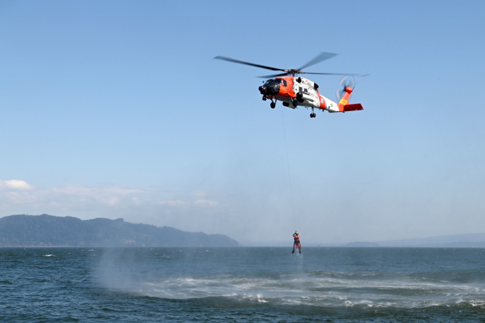 An MH-60 Jayhawk helicopter crew from Coast Guard Sector Columbia River hoists an aviation survival technician from the Columbia River during rescue training in Warrenton, Oregon, Tuesday, Apr.. 20, 2021. Coast Guard responders train to keep proficient and ready to respond at a moments notice to a call for help. U.S. Coast Guard photo by Petty Officer 1st Class Cynthia Oldham.