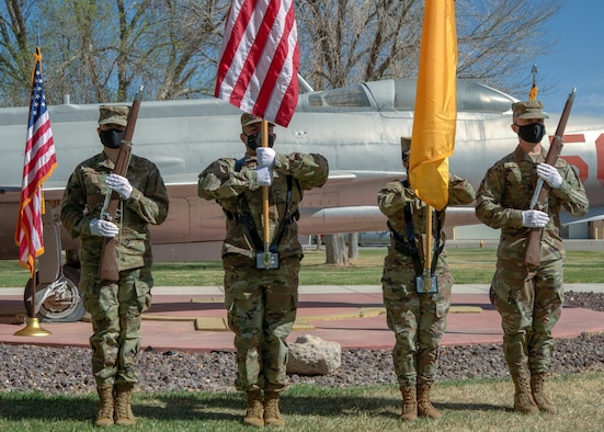 An honor guard stands in from of a static aircraft during a promotion ceremony.