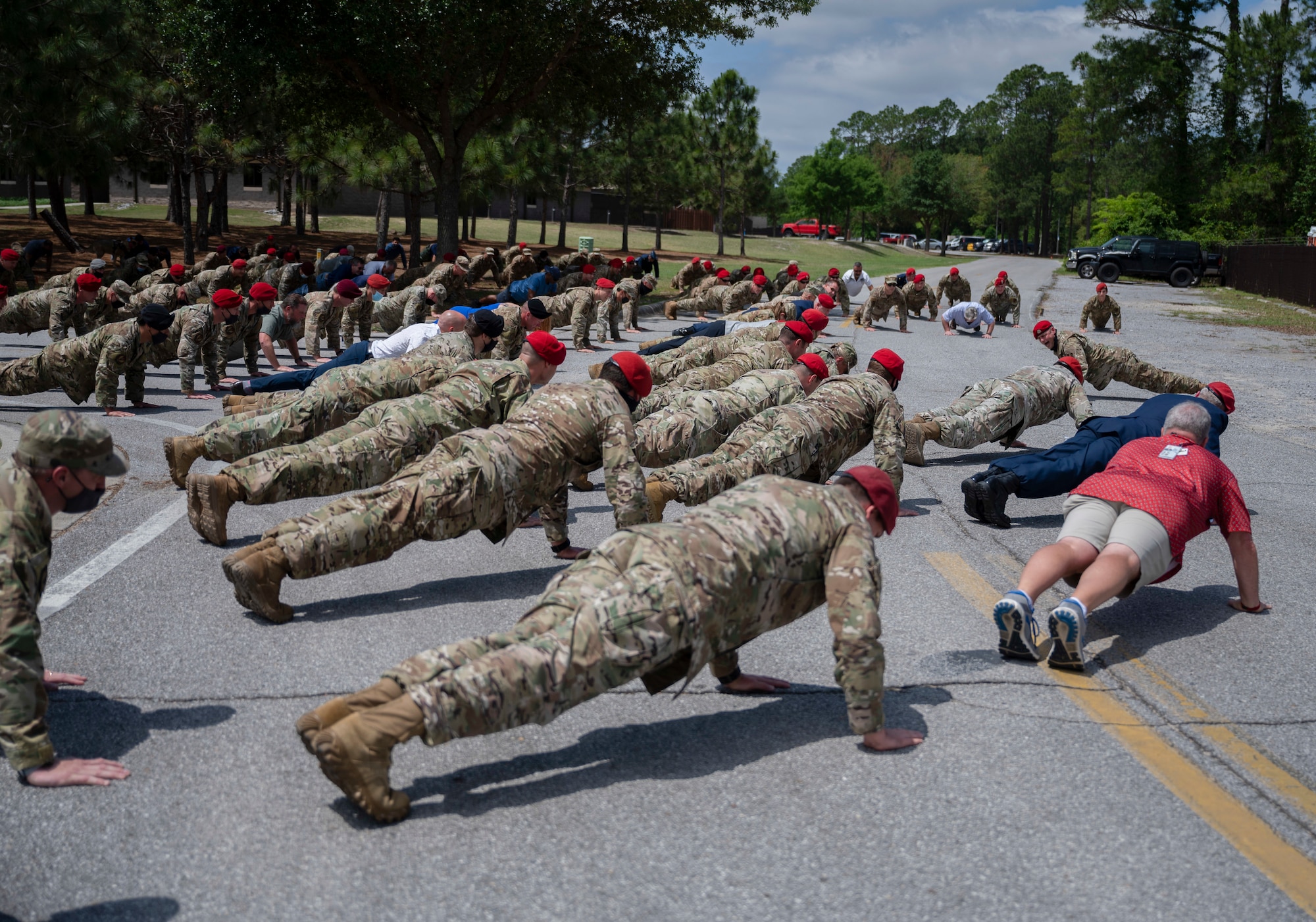 Special Tactics Airmen along with friends and family do memorial push-ups after a dedication ceremony.