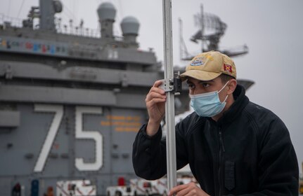 PORTSMOUTH, Va. (May 12, 2021) Interior Communications Electrician 3rd Class Devin Estapa, from Austin, Texas, uses a pole check to align the integrated fresnel lens optical landing system the flight deck of the Nimitz-class aircraft carrier USS Harry S. Truman (CVN 75). Truman departed Norfolk Naval Shipyard after completing a 10-month regularly scheduled extended carrier incremental availability. During the availability, the ship underwent maintenance, repair and inspection of various equipment to include engineering, combat systems, and nuclear propulsion. (U.S. Navy photo by Mass Communication Specialist 3rd Class Kelsey Trinh)