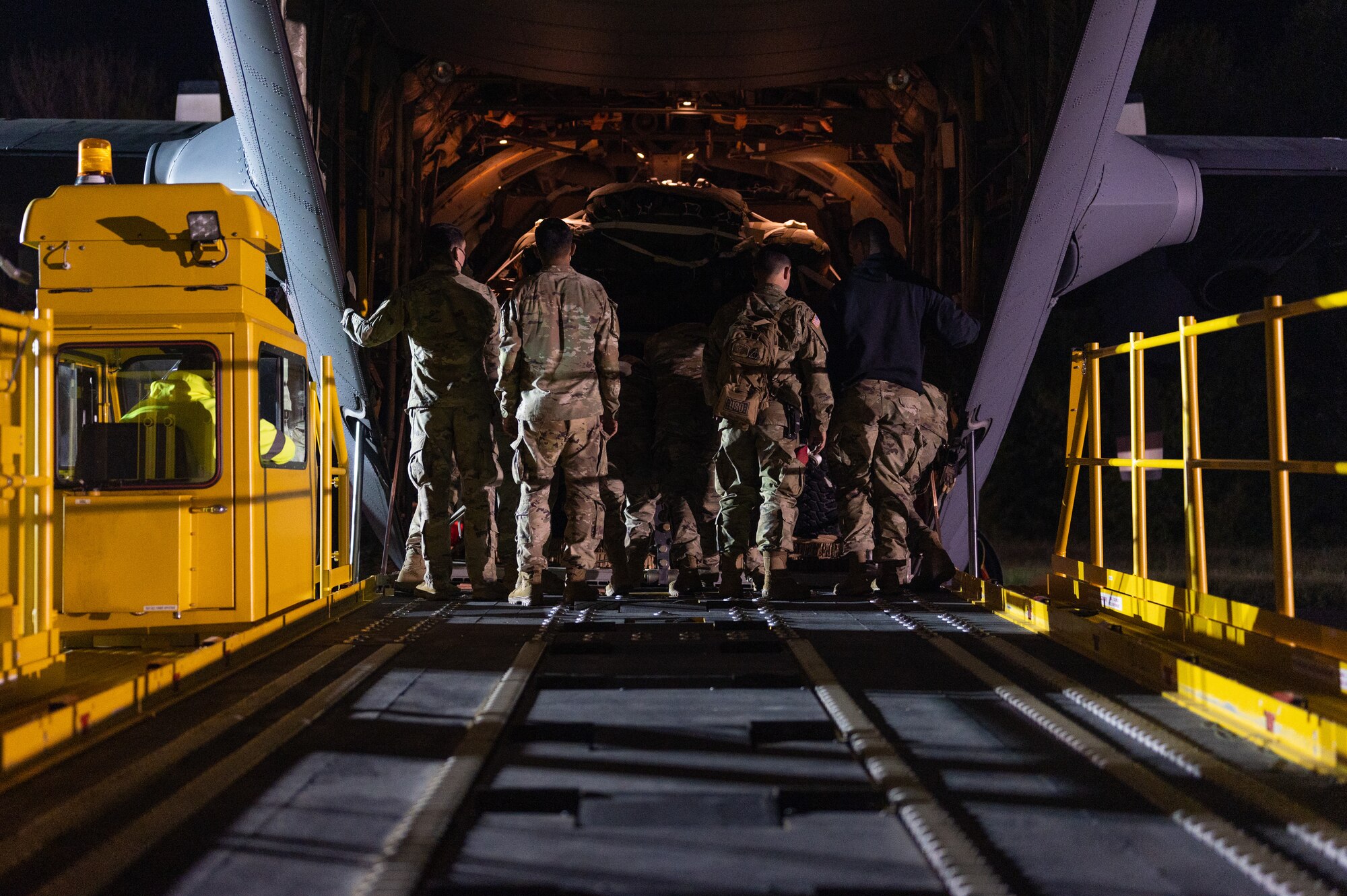 Airmen standing at the open ramp of an aircraft.