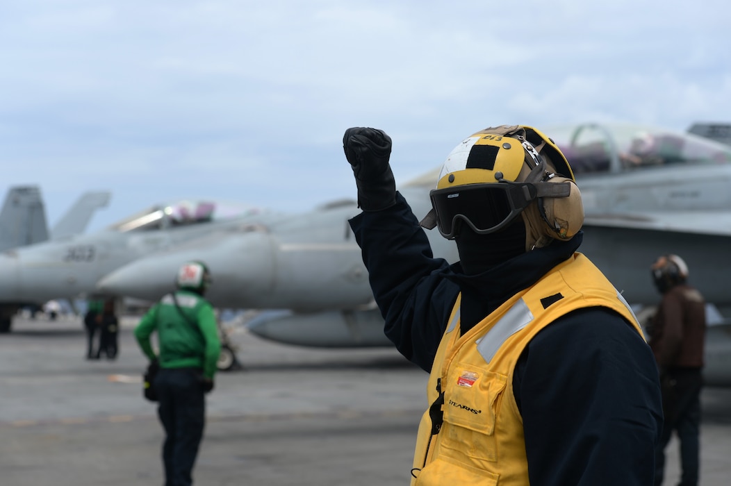 Aviation Boatswain's Mate (Handling) 1st Class Oliver Freeman, from Mandeville, Jamaica, directs traffic on the flight deck of the Nimitz-class aircraft carrier USS Harry S. Truman (CVN 75) during carrier qualifications after completing an extended incremental availability.