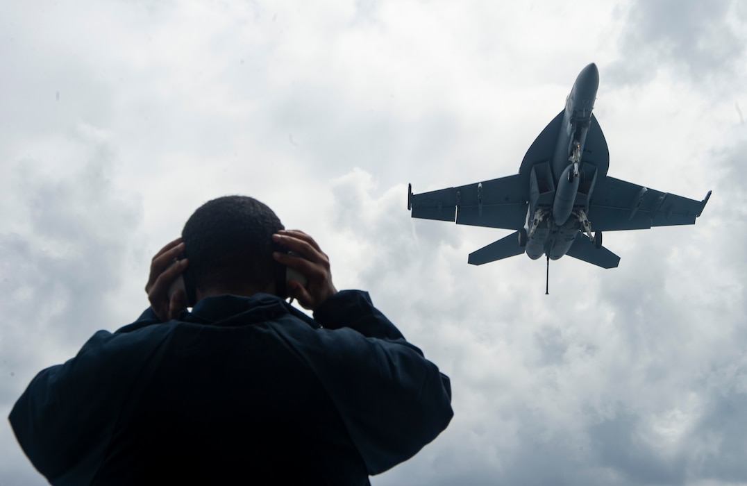 Seaman Terron Crestwell, from Manassas, Virginia, adjusts his sound-powered telephone headset as he observes an F/A-18E Super Hornet, attached to the "Blue Blasters" of Strike Fighter Squadron (VFA) 34, while standing lookout watch on the fantail of the Nimitz-class aircraft carrier USS Harry S. Truman (CVN 75) during carrier qualifications after completing an extended incremental availability.