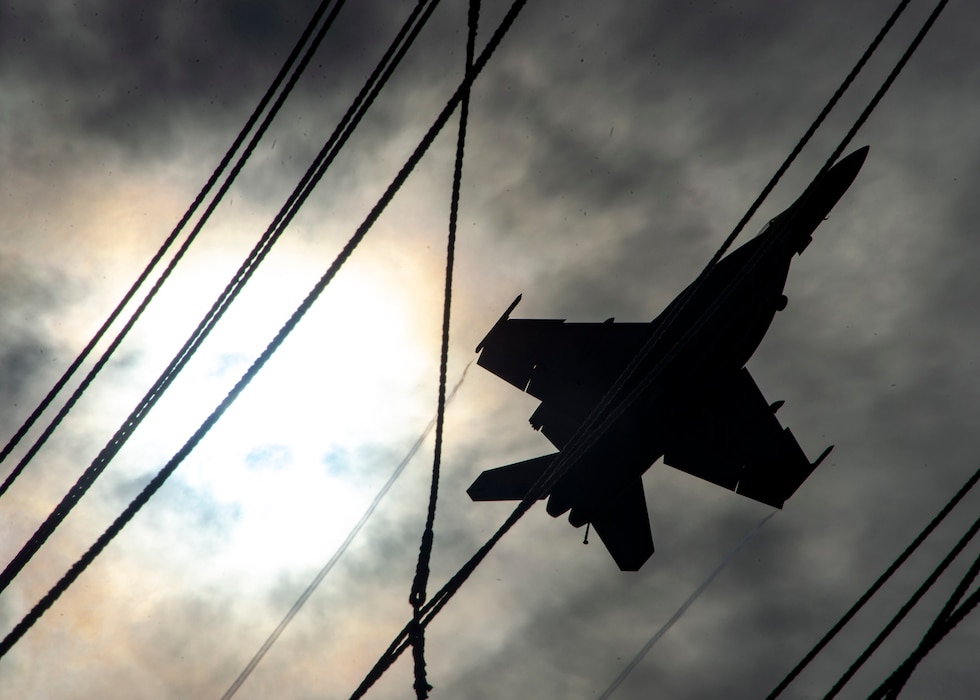 An F/A-18E Super Hornet, attached to the "Blue Blasters" of Strike Fighter Squadron (VFA) 34, flies over the Nimitz-class aircraft carrier USS Harry S. Truman (CVN 75) as seen through the flag and pennant lines during carrier qualifications after completing an extended incremental availability.