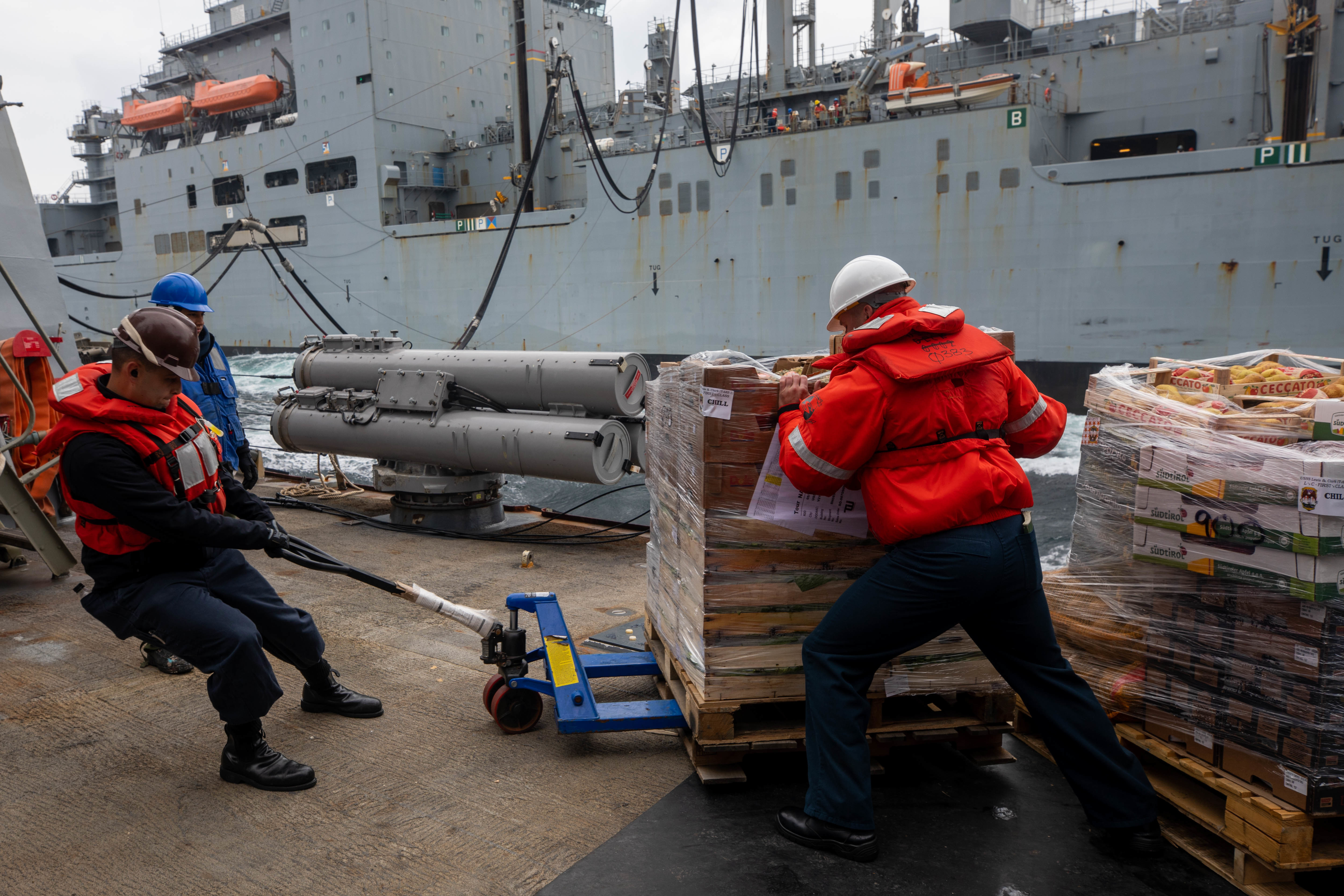 Culinary Specialist 1st Class Thomas Aduca, left, and Chief Interior Communications Electrician Benjamin Steinbrenner move a pallet of food stores during a replenishment-at-sea with the dry cargo ship USNS William McClean (T-AKE 12).