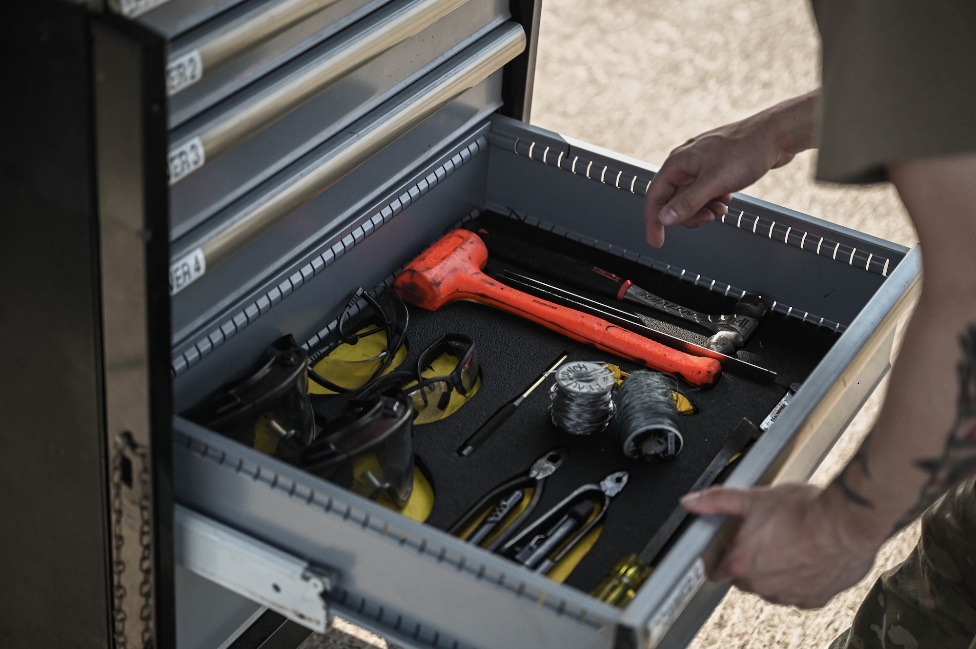 U.S. Air Force Senior Airman Paul Seagraves, a weapons load crew member with the 4th Aircraft Maintenance Unit, selects tools from a toolbox.