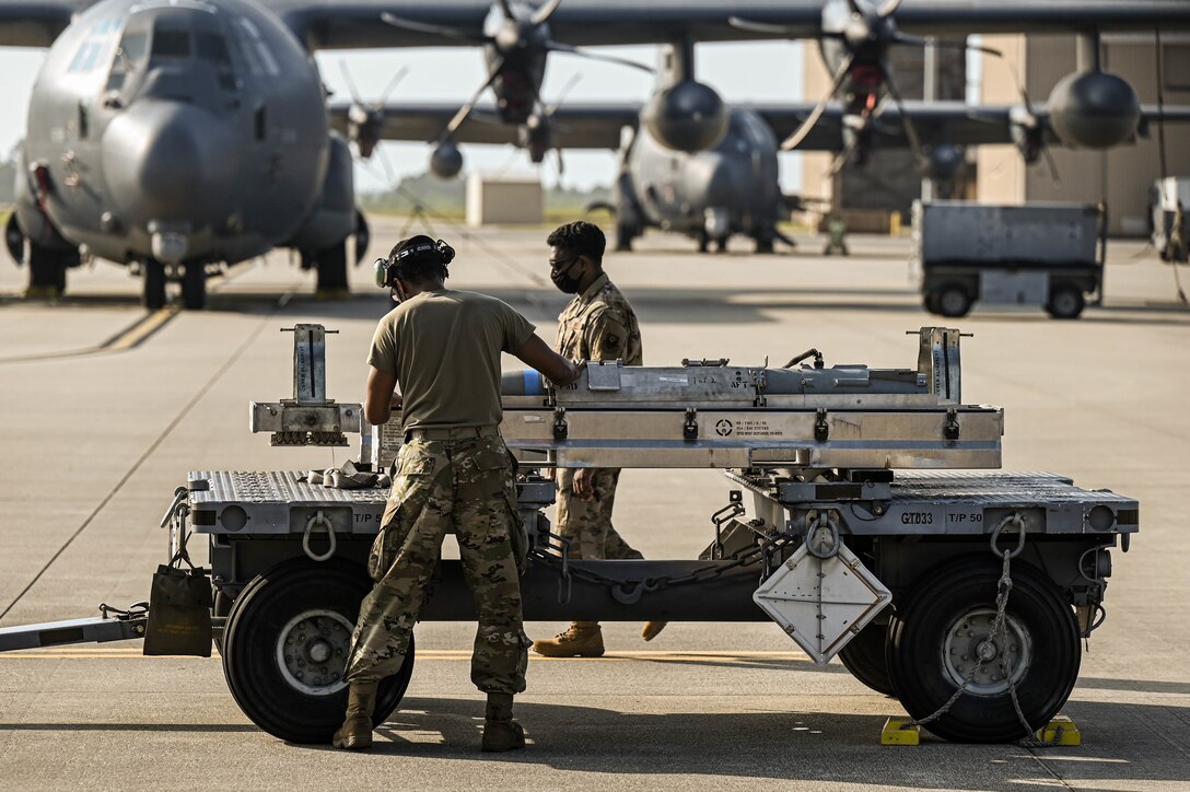 U.S. Air Force Airman 1st Class Michael Slaughter, a weapons load crew member with the 4th Aircraft Maintenance Unit, is evaluated by another Air Commando while delivering a guided bomb unit to an AC-130W AC-130W Stinger II gunship.