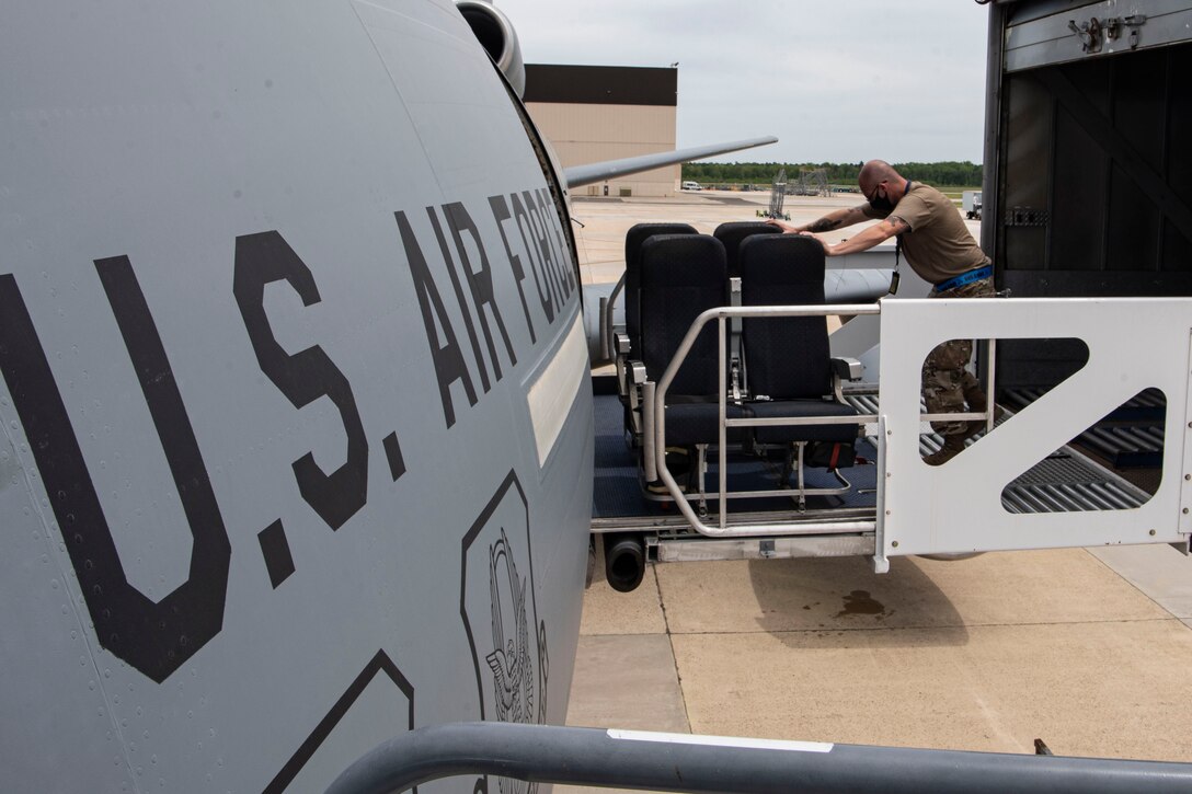 Photo of an Airman pushing seats onto a KC-10 Extender.
