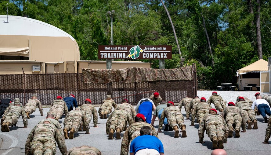 Special Tactics Airmen along with friends and family do memorial push-ups after a dedication ceremony.