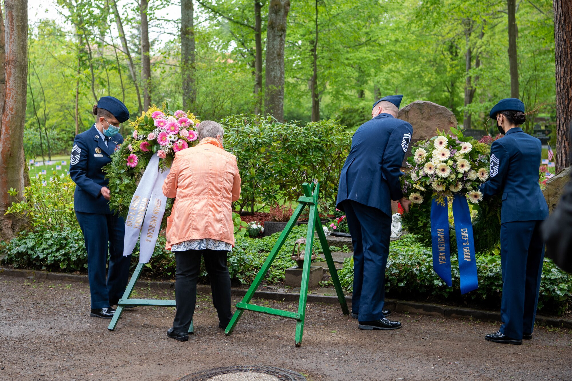 Service members and a civilian place wreaths for display