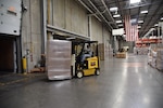 A forklift drives a pallet of packages onto the back of a truck.