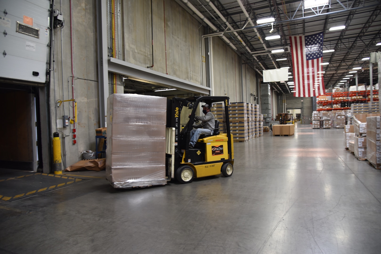 A forklift drives a pallet of packages onto the back of a truck.