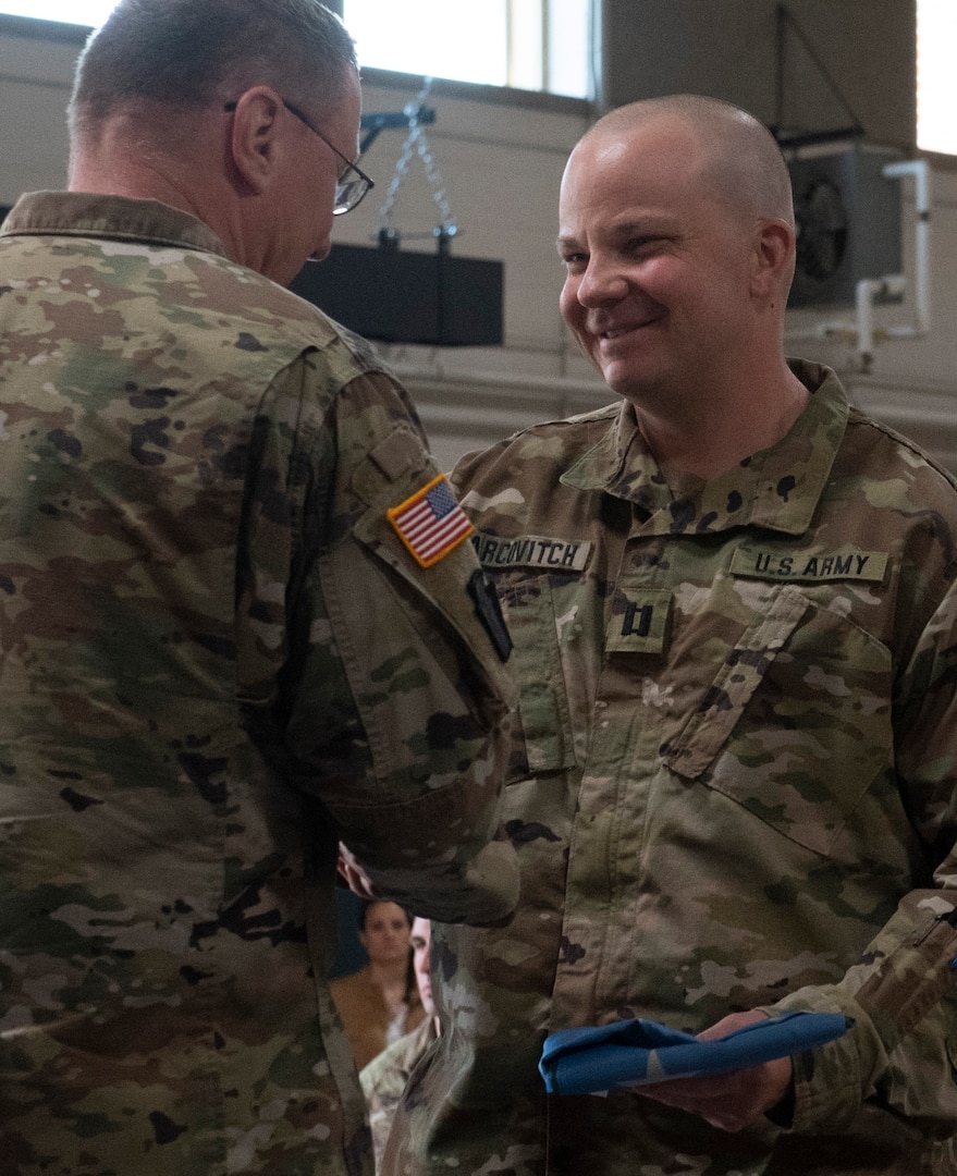 Capt. Mikel Arcovitch, commander of the 172nd Public Affairs Detachment, receives a Vermont battle flag from Maj. Gen. Greg Knight, the state adjutant general, during a sendoff ceremony for Task Force Mansfield and the 172nd PAD at Camp Johnson, Vermont, May 18, 2021. The 172nd PAD will document U.S. Army operations in the U.S. European Command area of responsibility. (U.S. Army National Guard photo by Don Branum)