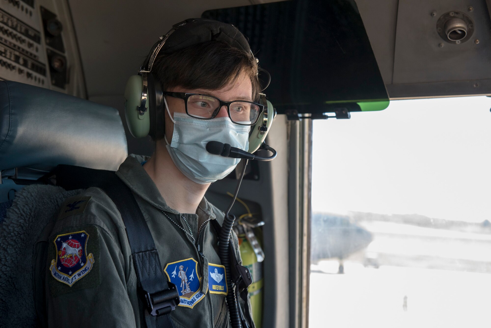 Hunter Willis receives mission instructions from the pilots through his headset before taking off on a training flight during a commander for the day event at the 167th Airlift Wing, Martinsburg, West Virginia, May 13, 2021. Willis, a local area resident diagnosed with a terminal illness, was invited to the 167th to serve as the wing commander for the day. After he was sworn in as commander, Willis was mission briefed, flown on a C-17 Globemaster III aircraft training mission and promoted his father, Tom Willis, to Lieutenant Colonel. (U.S. Air National Guard photo by Senior Airman Edward Michon).