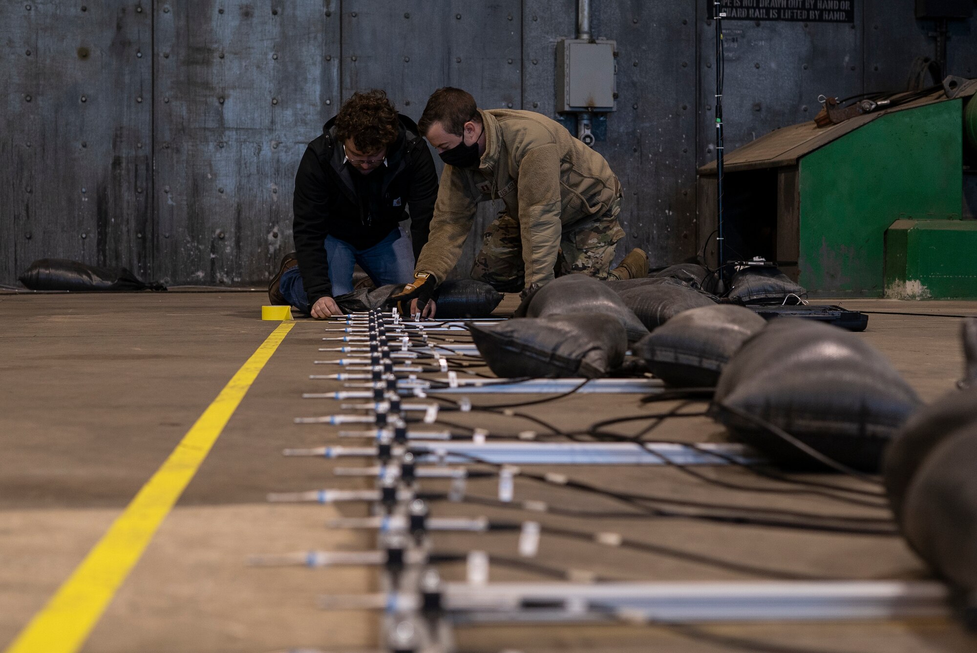 U.S. Air Force Capt. Christopher Hopkins, systems sensory engineer, and Conner Campbell, an acoustic monitoring technician, both stationed at Wright-Patterson Air Force Base, Ohio, calibrate monitoring devices prior to an F-35A Lightning II acoustic and emission test at Royal Air Force Lakenheath, England, May 4, 2021. The sensors monitor the acoustic levels present in the shelter during different stages of an engine run. (U.S. Air Force photo by Senior Airman Jessi Monte)