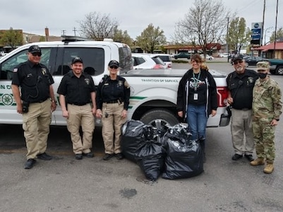 Police, a soldier and civilians pose for photo with garbage bags of prescriptions.