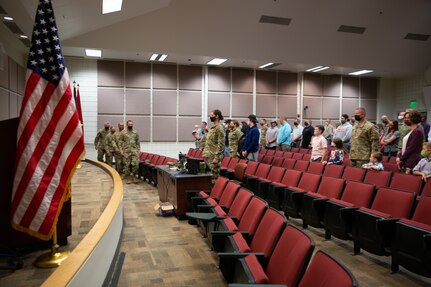 Soldiers and family members stand in an auditorium
