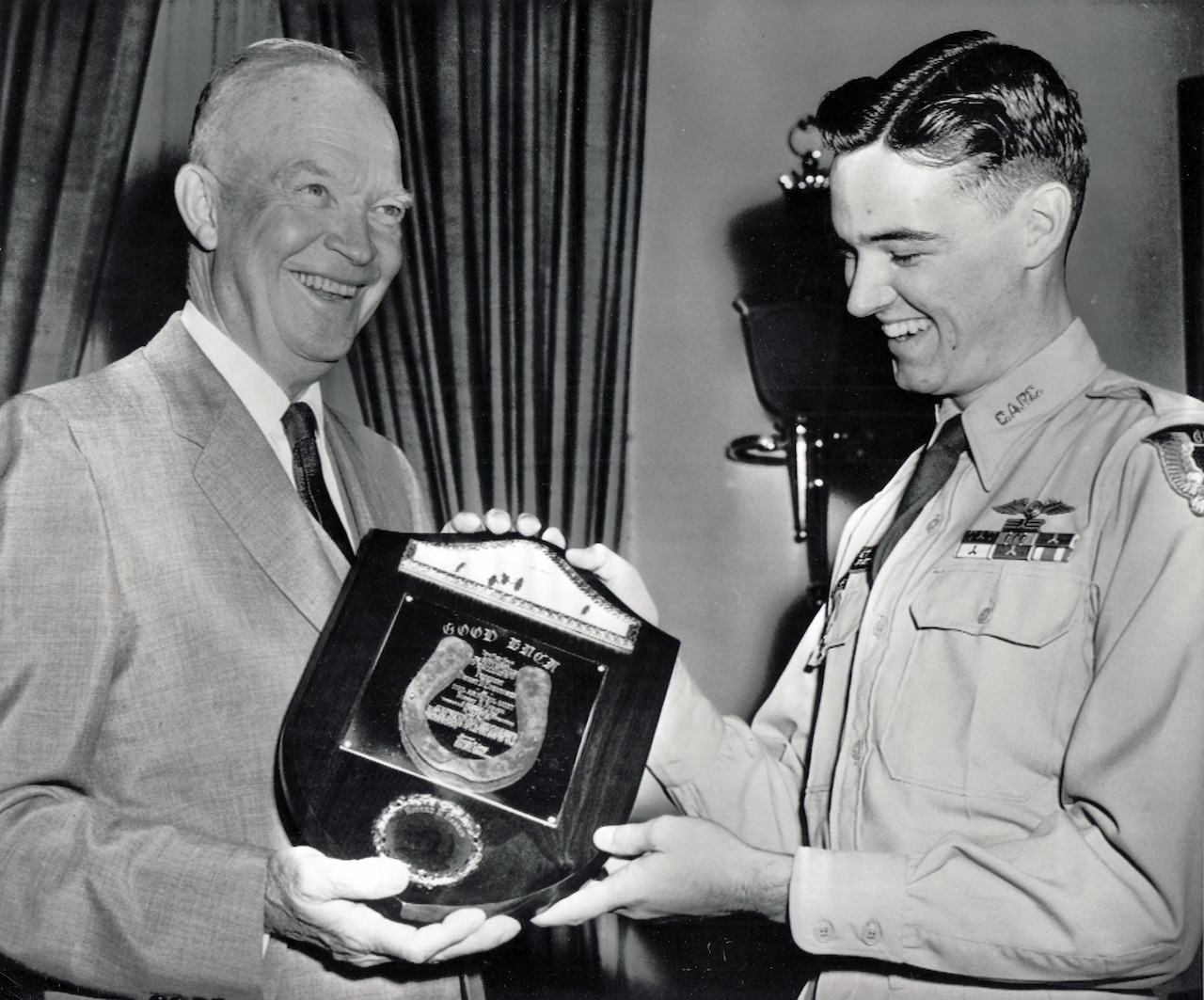 Two men smile while they hold a plaque.