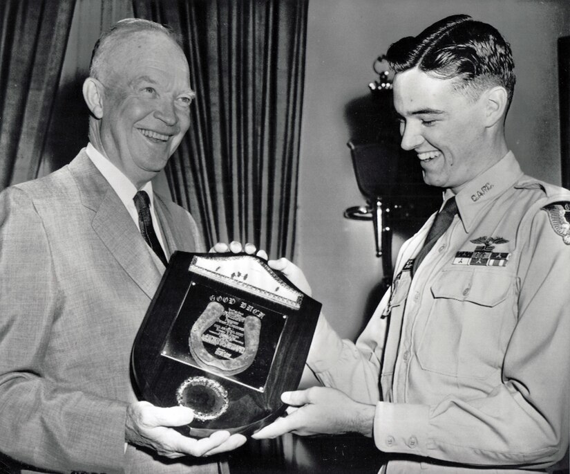 Two men smile while they hold a plaque.