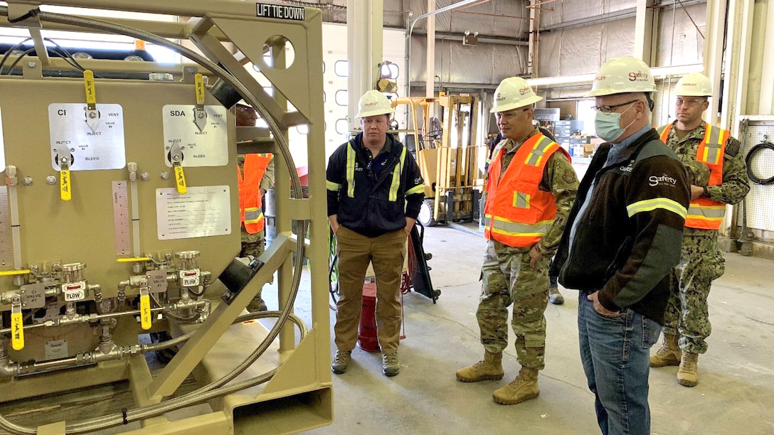 three men look at a fuel additive injection system