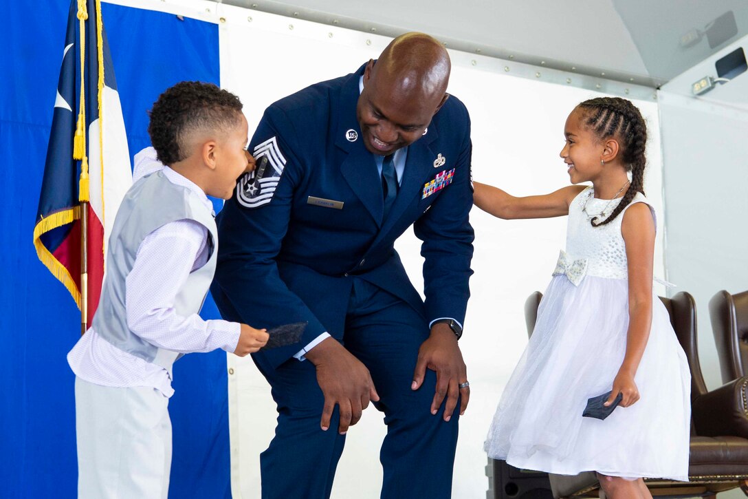 An airman stands between two children.