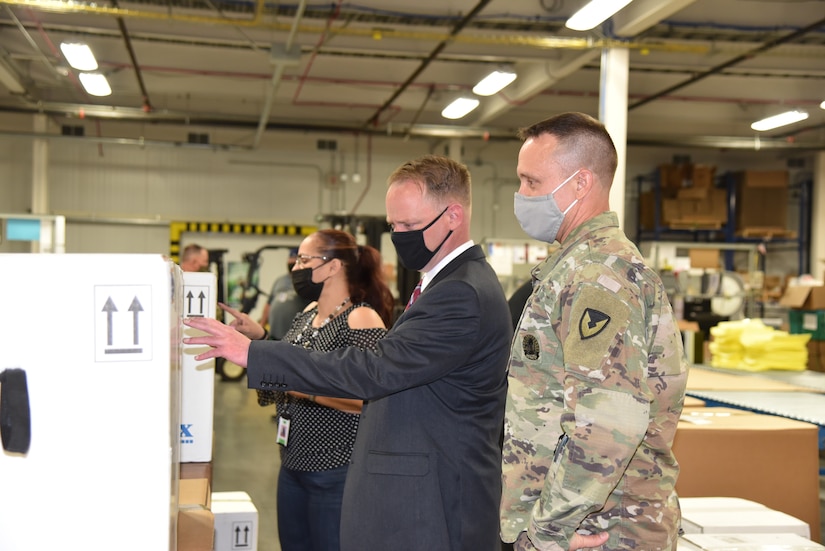 A woman and two men look into a box.