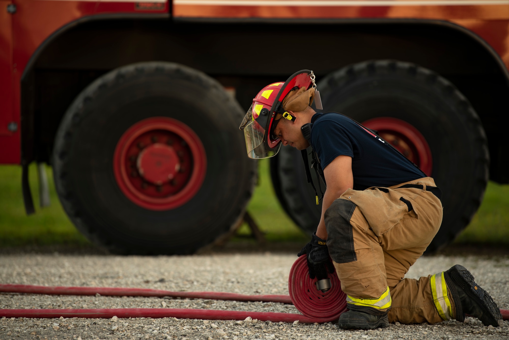 U.S. Air Force firefighter assigned to the 36th Civil Engineer Squadron, rolls up a fire hose during joint aircraft fire training at Andersen Air Force Base, Guam, May 11, 2021.