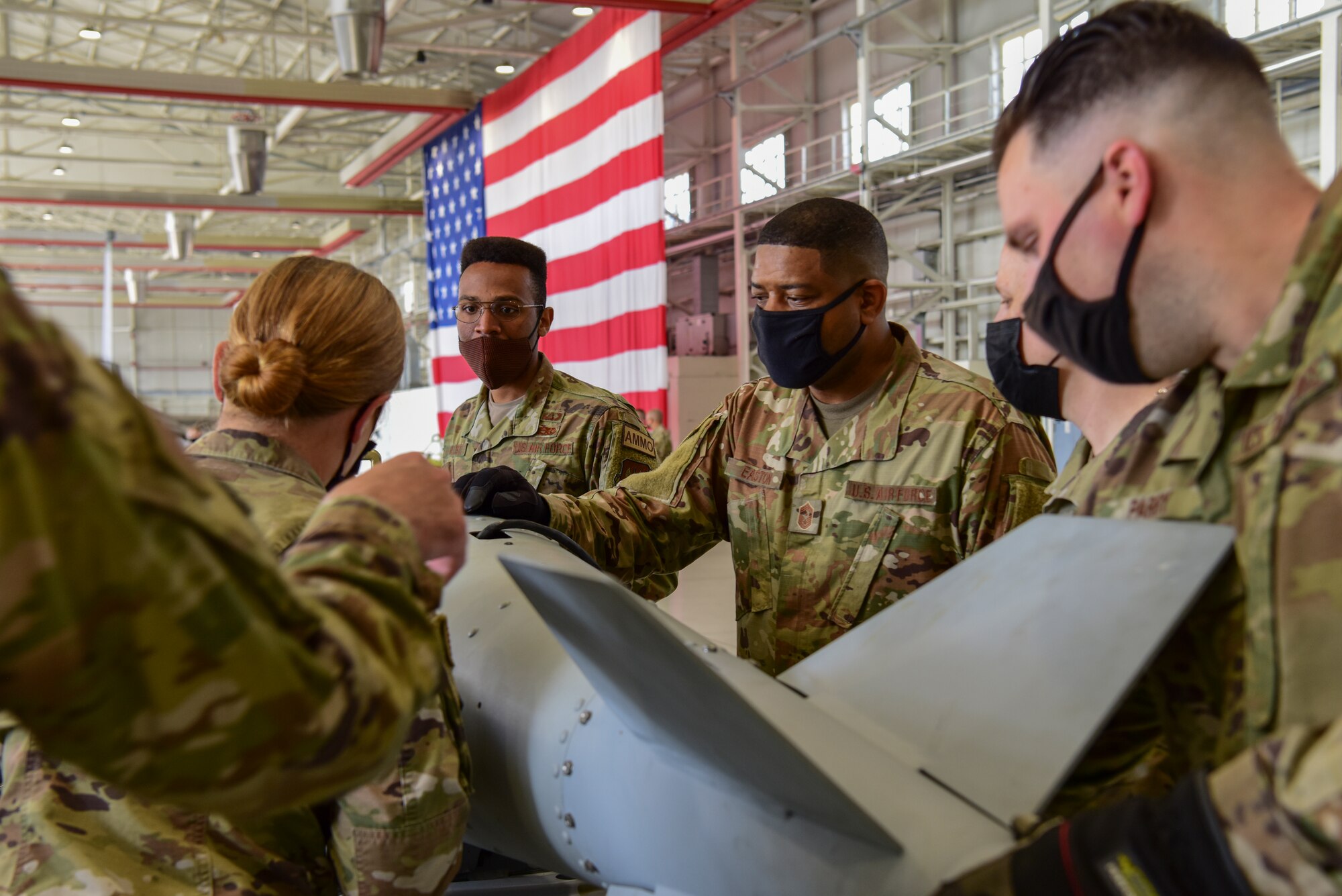 Chief Master Sgt. Phillip Easton, U.S. European Command senior enlisted leader, (center) participates in a bomb build with the 31st Munitions Squadron Airmen at Aviano Air Base, Italy, May 13, 2021. During his visit Easton saw practical projects with a more hands-on approach. During the bomb build Easton helped install various components to the munition with the help of Munitions Squadron Airmen while getting to know them and their job. (U.S. Air Force photo by Senior Airman Jessica Blair)