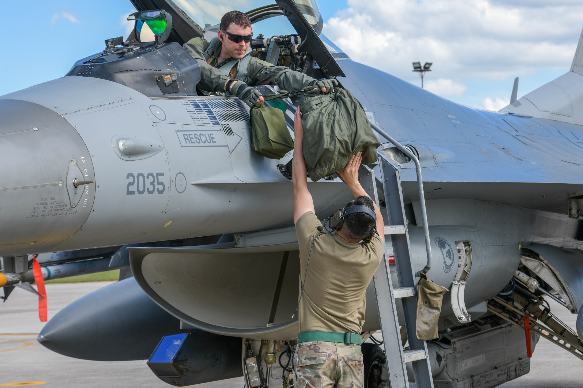 U.S. Air Force Maj. John Hamilton, 555th Fighter Squadron F-16 Fighting Falcon pilot, hands a flight equipment bag to Senior Airman Juan Monroy, 555th Aircraft Maintenance Unit F-16 crew chief, after participating in Astral Knight 2021 (AK21) at Aviano Air Base, Italy, May 18, 2021. AK21 is a U.S. Air Forces in Europe-Air Forces Africa-led exercise involving Airmen, Soldiers and Sailors from the U.S. working with members from Albania, Croatia, Greece, Italy and Slovenia. AK21 is an integrated air and missile defense exercise focused on defending key terrain. (U.S. Air Force photo by Airman 1st Class Brooke Moeder)