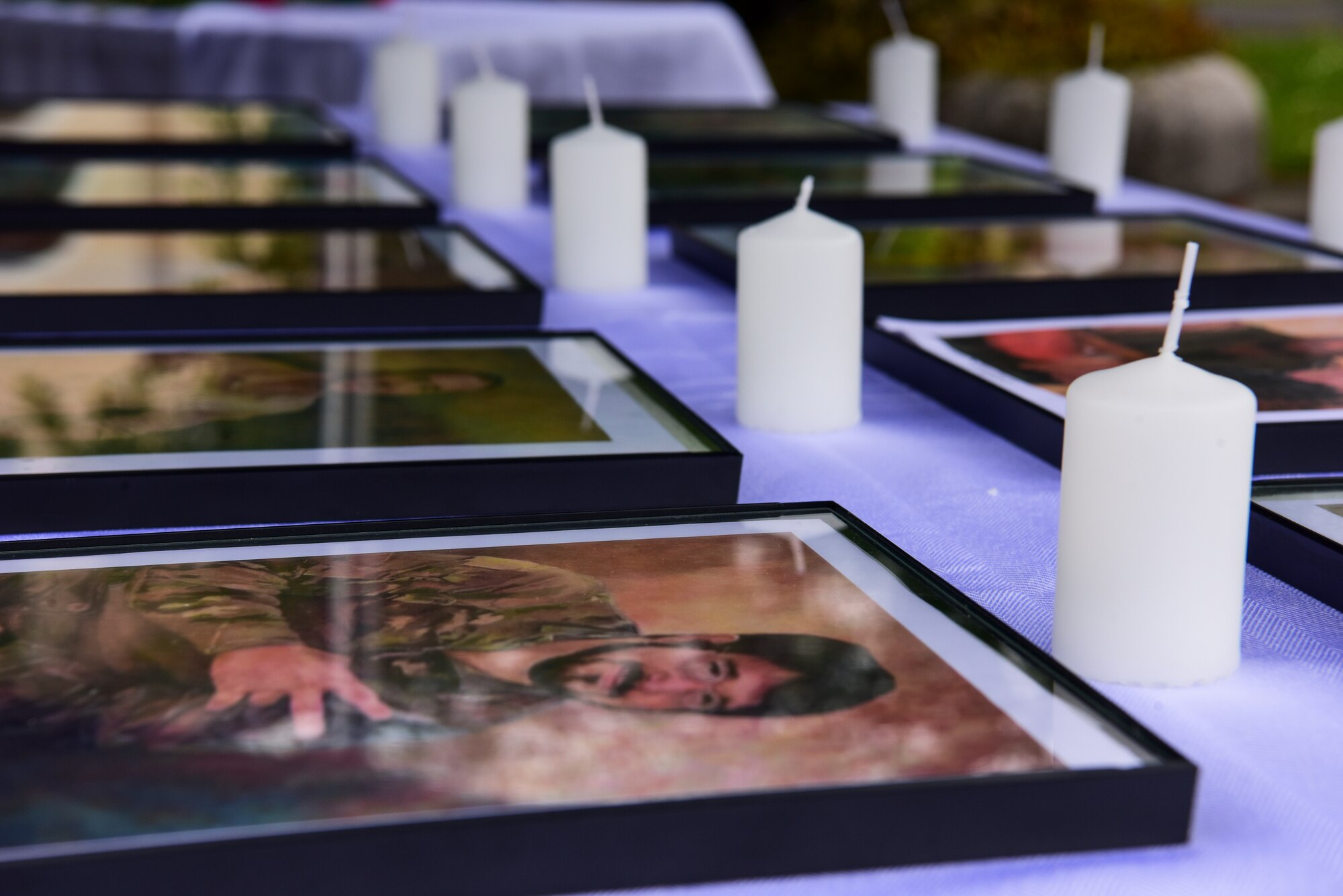 Memorial photos of fallen service members are displayed on a table during a memorial ceremony at Aviano Air Base, Italy, May 14, 2021. The 31st Fighter Wing held a memorial ceremony during retreat on the last day of Police Week to honor all past, fallen military and civilian law enforcement officers for their ultimate sacrifice and to thank current defenders for their continued efforts to keep the Wyvern community safe. During the ceremony there was a formation of defenders, display of Humvees, and a photo and rose bearing session. (U.S. Air Force photo by Senior Airman Jessica Blair)