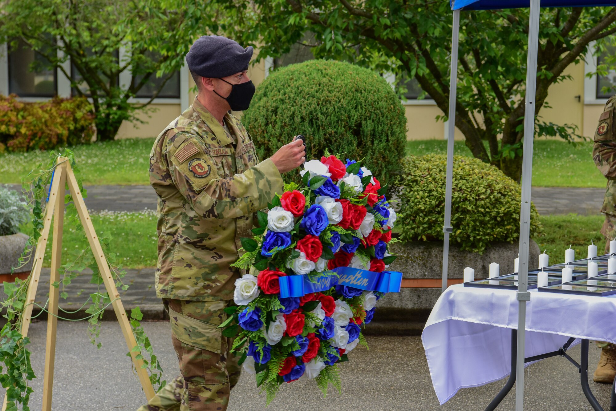 Chief Master Sgt. Javier Gonzalez, 31st Security Forces Squadron security forces manager, carries a wreath to the battle cross memorial at Aviano Air Base, Italy, May 14, 2021. The battle cross is a representative replacement of a cross on the battlefield for a soldier who has passed away. The battle cross is made up of the soldier's rifle, boots, helmet and dog tags, to show honor and respect at the battle site. (U.S. Air Force photo by Senior Airman Jessica Blair)